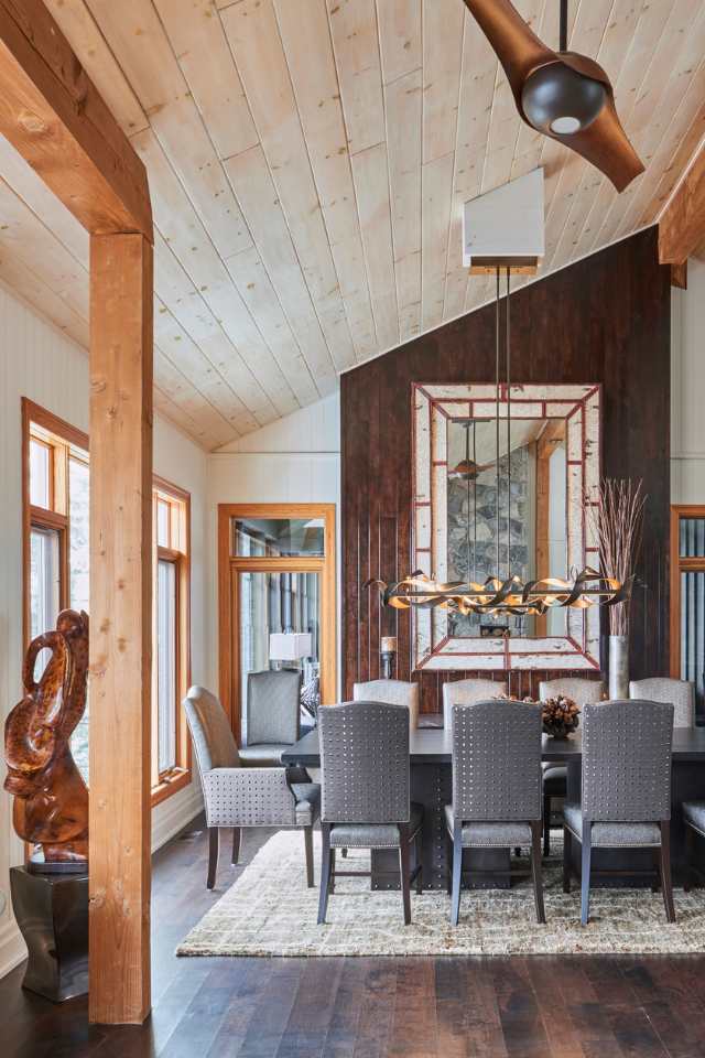 rustic cabin dining room with vaulted wood ceilings, wooden beams, and bronze chandeliers